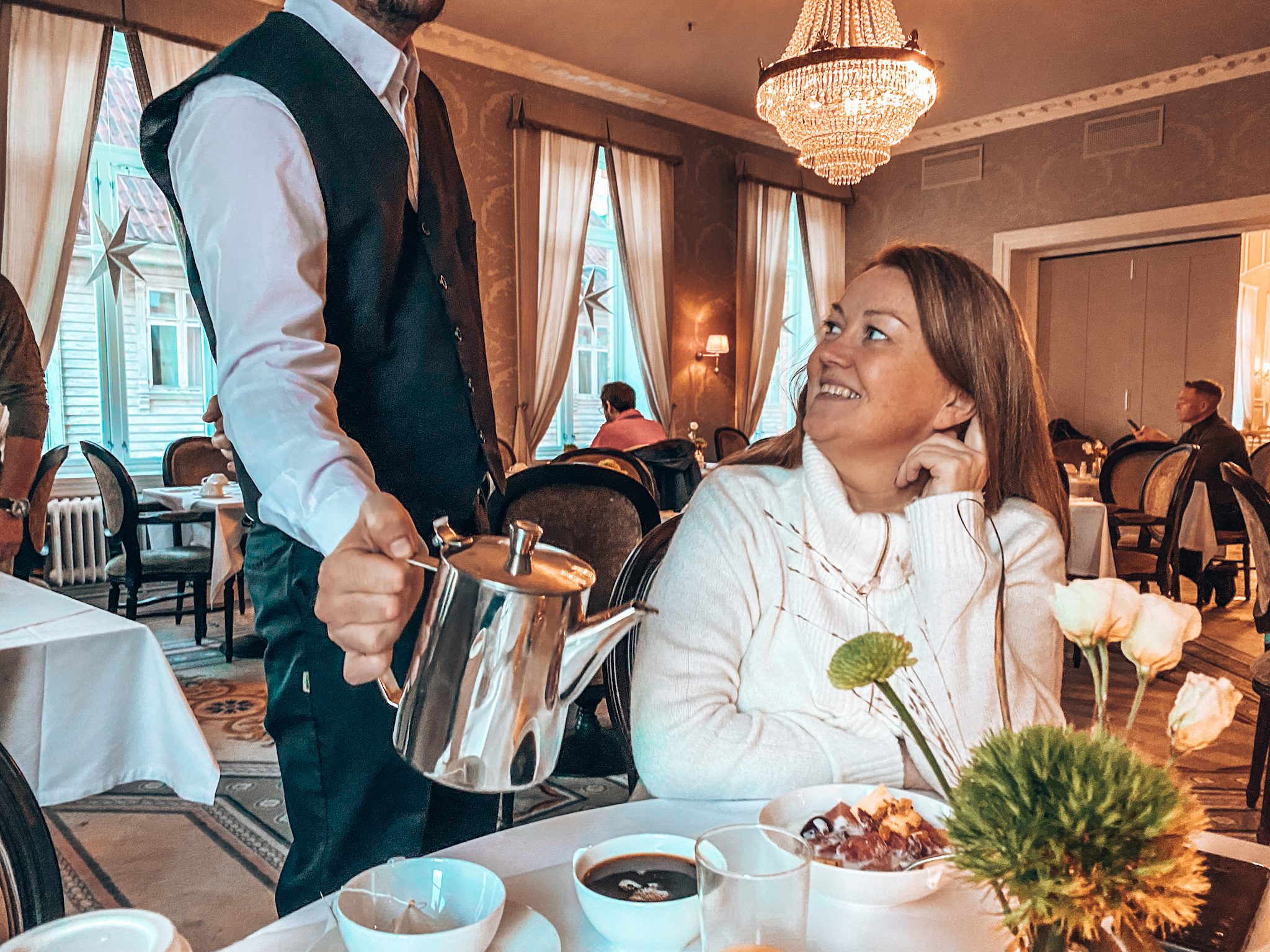 Hotellfrokoster på Jæren, kvinne serveres kaffe fra sølvkanne av kelner i pent antrekk.