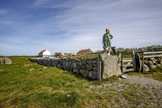 Hå gamle prestegard med kvinne på toppen av en steinmur