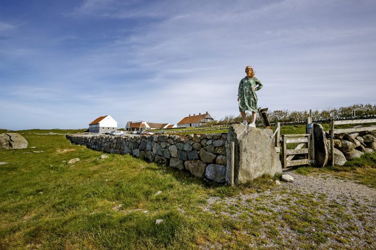 Hå gamle prestegard med kvinne på toppen av en steinmur