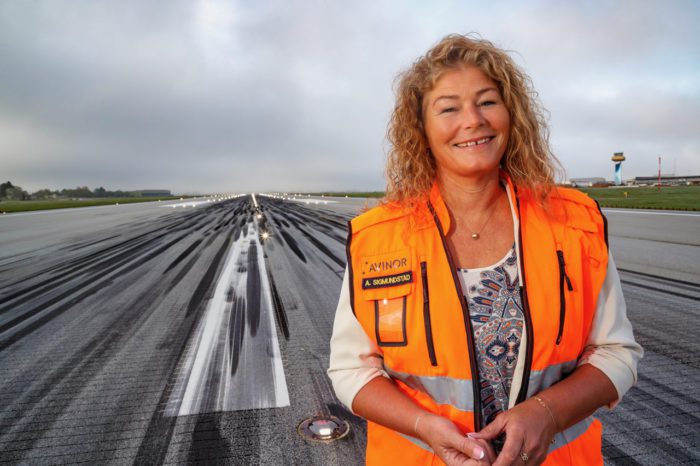 Avinor, kvinne i vest som står på en rullebane